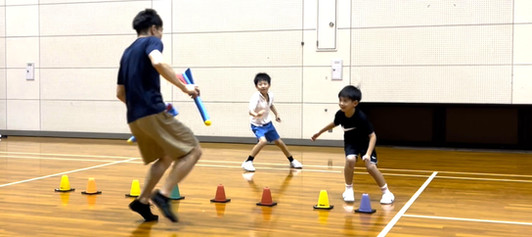 加賀市教室にて、楽しそうにおにごっこをする男児2人と大久保先生