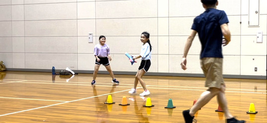 加賀市教室にて、オリジナルの「ロケットおに」をする小学生の女児２人と大久保先生