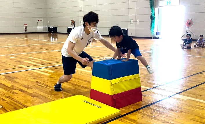 小松市教室にて、跳び箱をする幼児と補助をする大久保先生