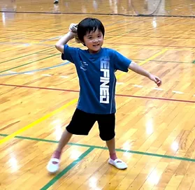 笑顔でボール投げの練習をする幼児