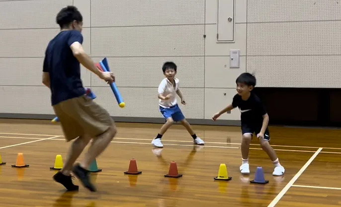 楽しそうに鬼ごっこをする小学３年の男の子二人と大久保先生