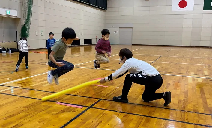 反応トレーニングで、棒に引っかからないようにジャンプしている男の子二人