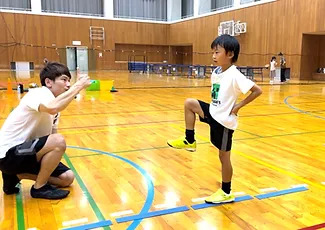 金沢市教室にて、走り方の練習「片足バランス」をする小学生の子供と指導する大久保先生