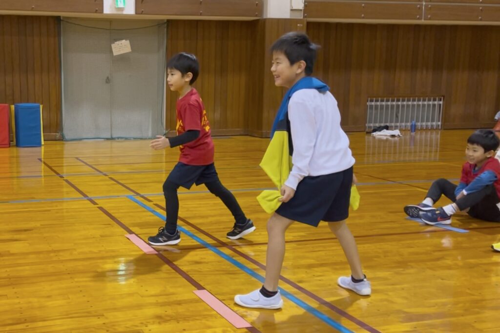 金沢市教室の冨樫教育プラザ体育館にて、楽しそうに反応トレーニングをする笑顔の小学生男児二人