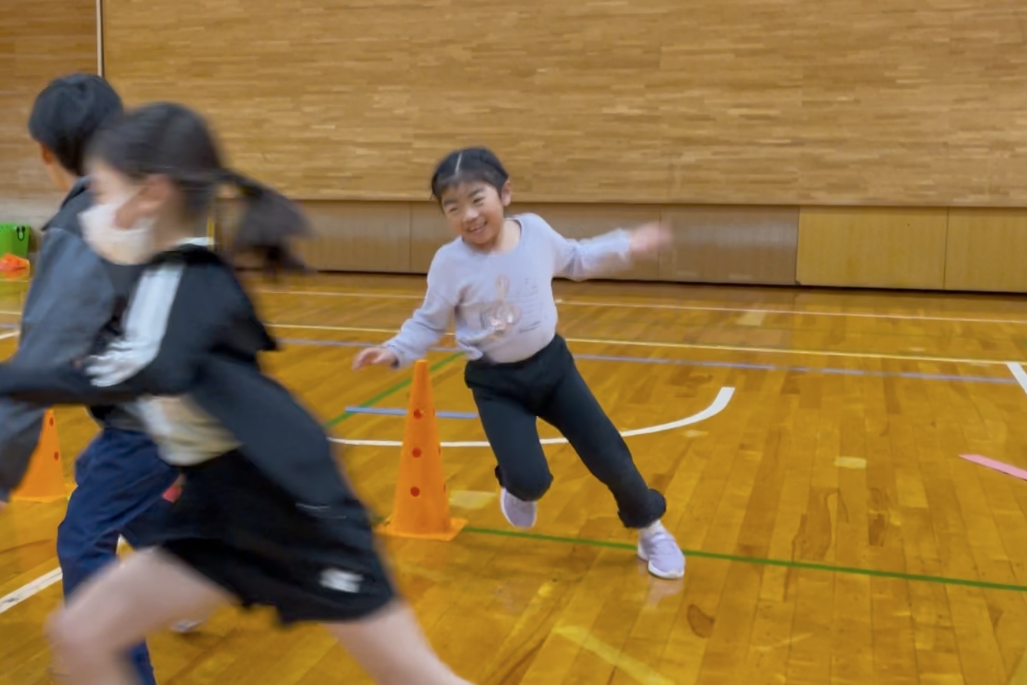 福井市教室にて、笑顔で鬼ごっこをして友達を追いかける小学生の女児の子供