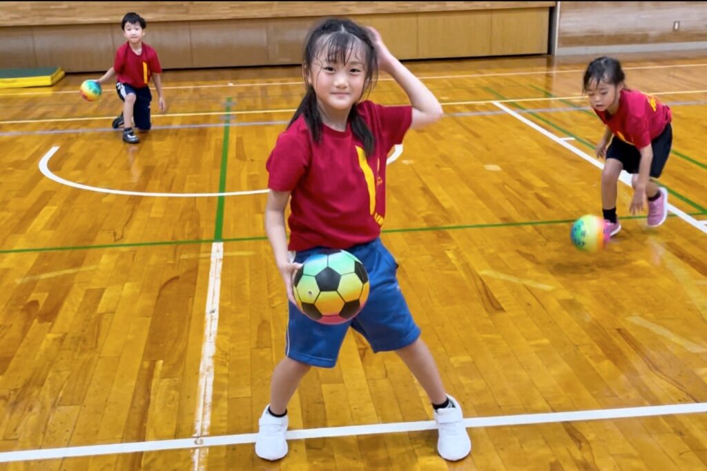 福井市教室にて、笑顔でボールコントロールの練習をする小学生女児の子供